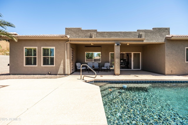 rear view of property with a patio area, stucco siding, and an outdoor pool