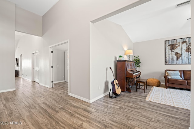 sitting room with arched walkways, baseboards, visible vents, and light wood-style flooring