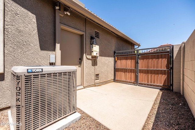 view of patio featuring fence, cooling unit, and a gate