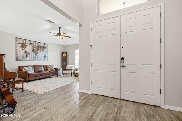foyer entrance featuring ceiling fan, visible vents, baseboards, and light wood-type flooring