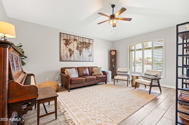 living area featuring baseboards, wood tiled floor, and ceiling fan