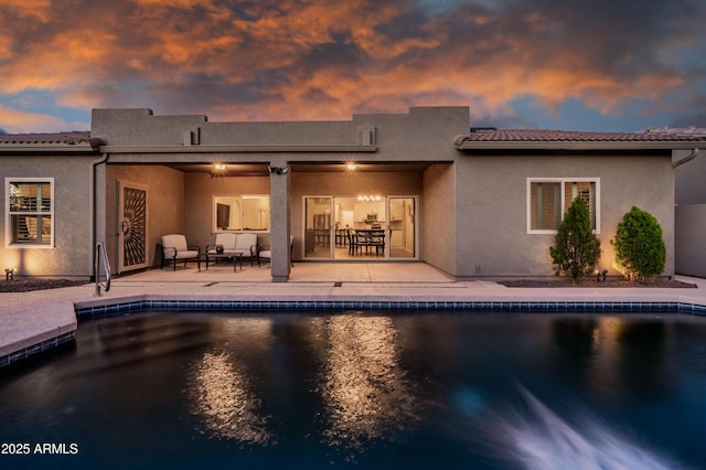 back of house with an outdoor pool, a patio area, and stucco siding