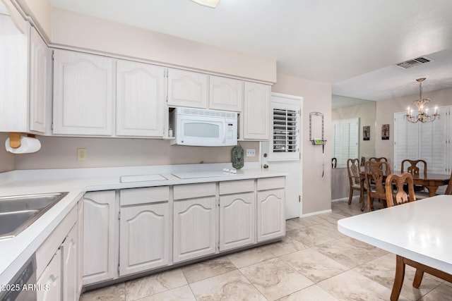 kitchen featuring sink, dishwasher, white cabinets, decorative light fixtures, and a chandelier