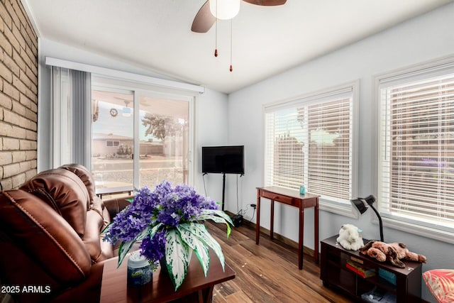 living area featuring vaulted ceiling, brick wall, hardwood / wood-style floors, and ceiling fan