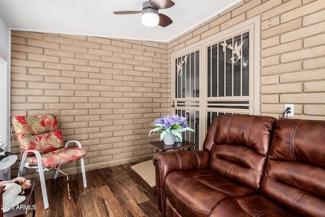 interior space with ceiling fan, brick wall, and dark hardwood / wood-style flooring