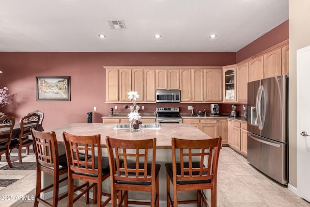 25845 N 44th Ave, Phoenix, AZ 85083 - kitchen with visible vents, light brown cabinetry, glass insert cabinets, an island with sink, and appliances with stainless steel finishes