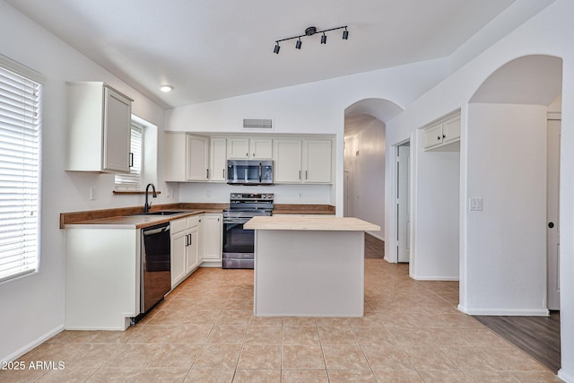 kitchen featuring visible vents, lofted ceiling, arched walkways, stainless steel appliances, and a sink