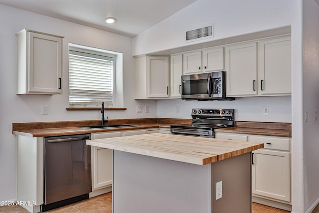 kitchen featuring visible vents, a sink, a center island, appliances with stainless steel finishes, and butcher block counters