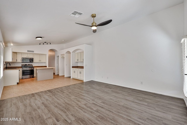 kitchen with visible vents, light wood-type flooring, arched walkways, stainless steel appliances, and open floor plan