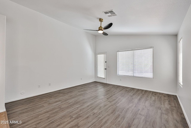 spare room featuring visible vents, lofted ceiling, wood finished floors, baseboards, and ceiling fan