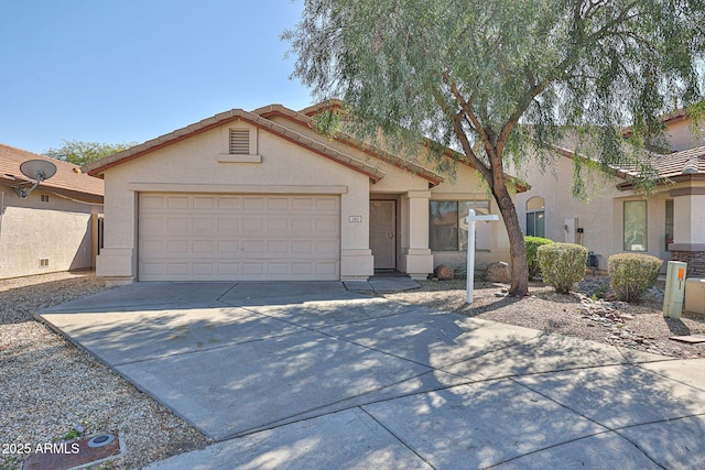 ranch-style house featuring a tiled roof, stucco siding, an attached garage, and concrete driveway