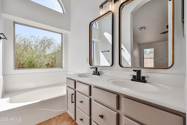 bathroom featuring visible vents, double vanity, a sink, tile patterned floors, and a bath