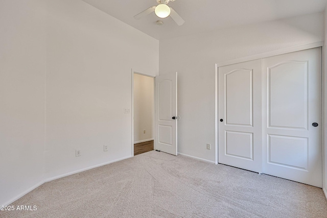 unfurnished bedroom with a closet, carpet floors, baseboards, and a ceiling fan