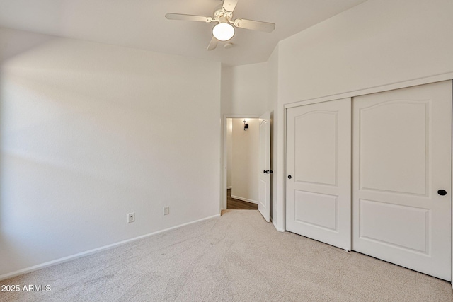 unfurnished bedroom with light carpet, ceiling fan, baseboards, and a closet