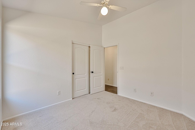 spare room with baseboards, carpet, lofted ceiling, and a ceiling fan