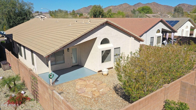 rear view of property with a mountain view, a patio, a fenced backyard, and a tile roof