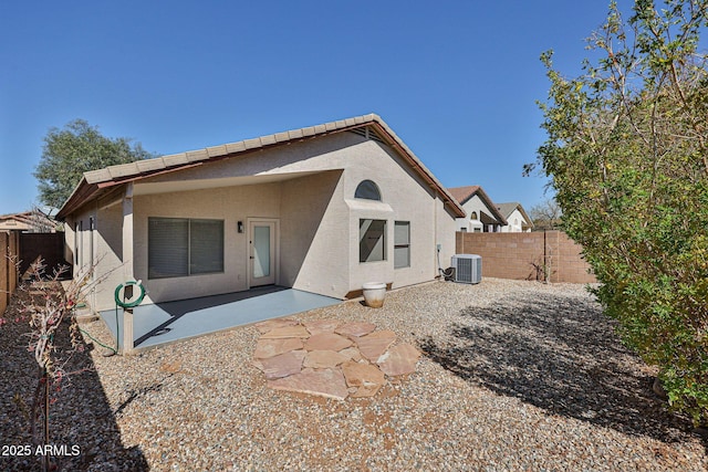 rear view of house with a patio area, a fenced backyard, central AC, and stucco siding