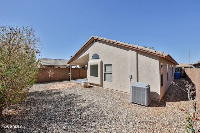 rear view of house featuring a fenced backyard, stucco siding, a patio, and central AC