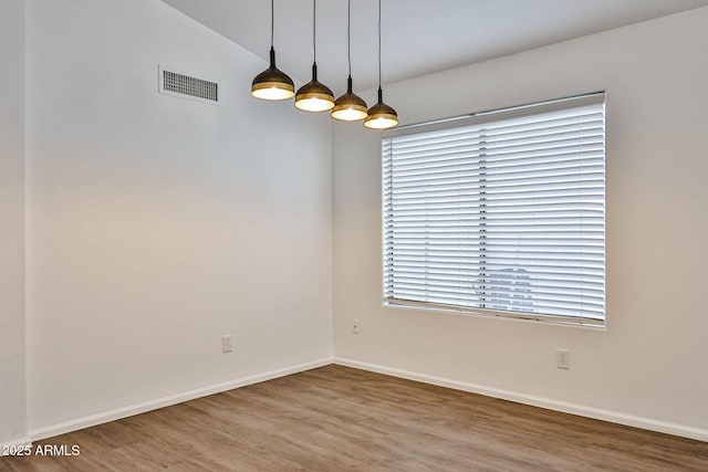 spare room featuring lofted ceiling, wood finished floors, visible vents, and baseboards