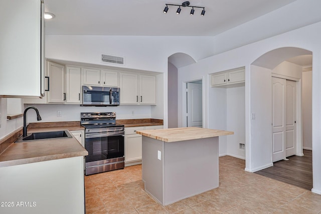 kitchen featuring visible vents, a sink, stainless steel appliances, vaulted ceiling, and butcher block counters