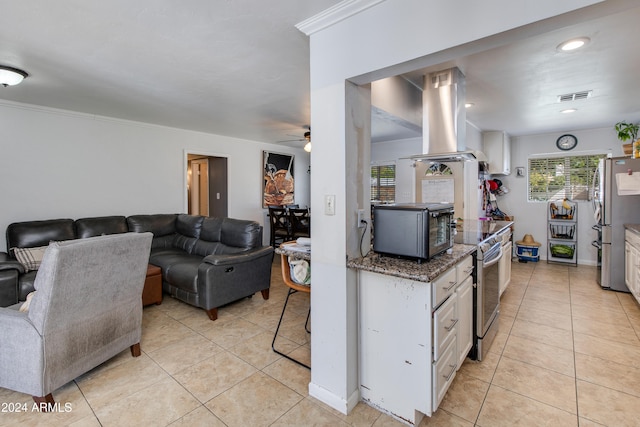 kitchen featuring appliances with stainless steel finishes, island range hood, white cabinetry, crown molding, and light tile patterned floors