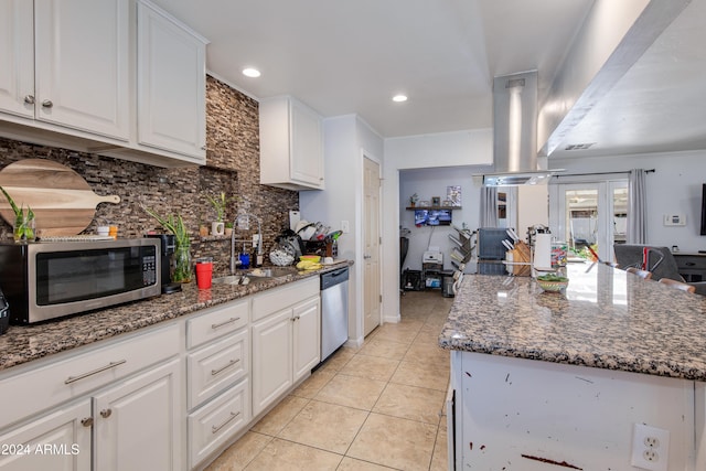 kitchen with appliances with stainless steel finishes, white cabinets, sink, and a kitchen island