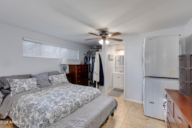 bedroom featuring a closet, light tile patterned flooring, connected bathroom, and ceiling fan