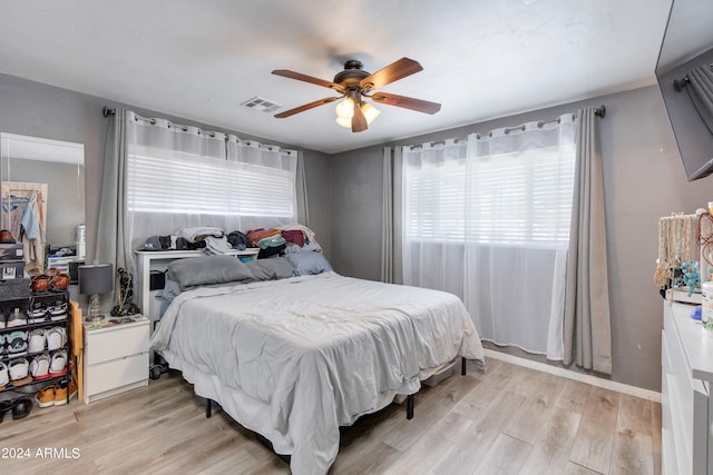 bedroom with light hardwood / wood-style floors, multiple windows, and ceiling fan