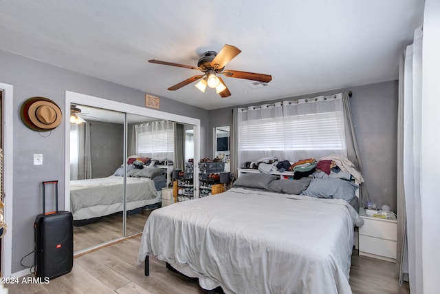 bedroom featuring light hardwood / wood-style flooring, multiple windows, a closet, and ceiling fan