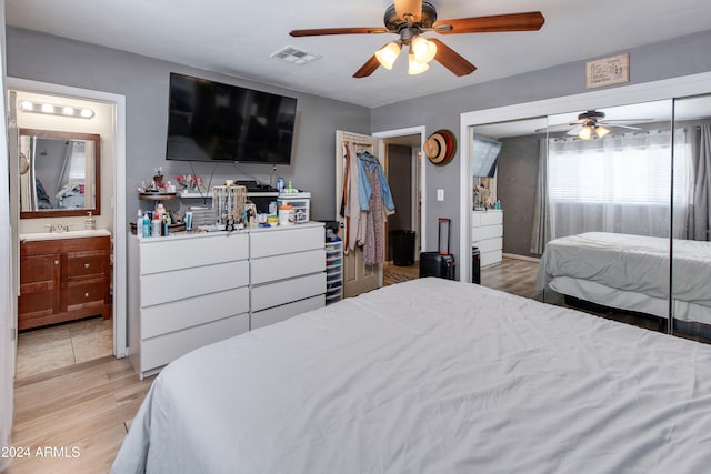 bedroom with ceiling fan, light wood-type flooring, ensuite bathroom, a closet, and sink