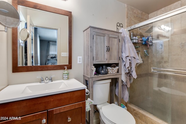 bathroom featuring vanity, toilet, and a shower with door