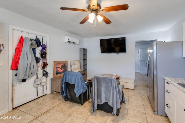 interior space with a wall mounted AC, stainless steel fridge, light tile patterned flooring, white cabinetry, and ceiling fan