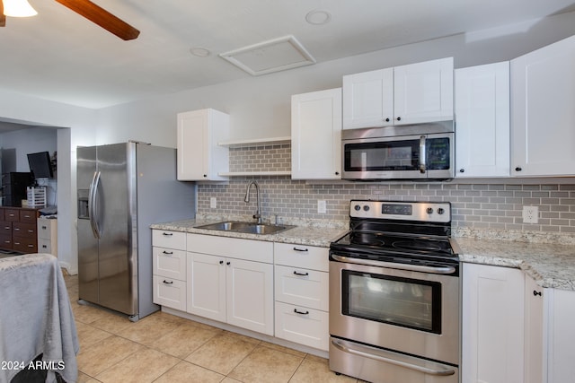 kitchen with sink, white cabinets, light tile patterned floors, appliances with stainless steel finishes, and tasteful backsplash