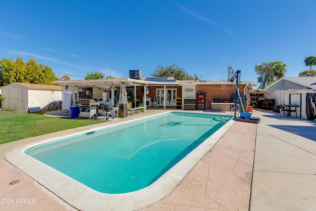 view of pool featuring a yard, a patio area, and a shed