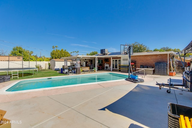 view of swimming pool with a trampoline, a patio area, and a lawn