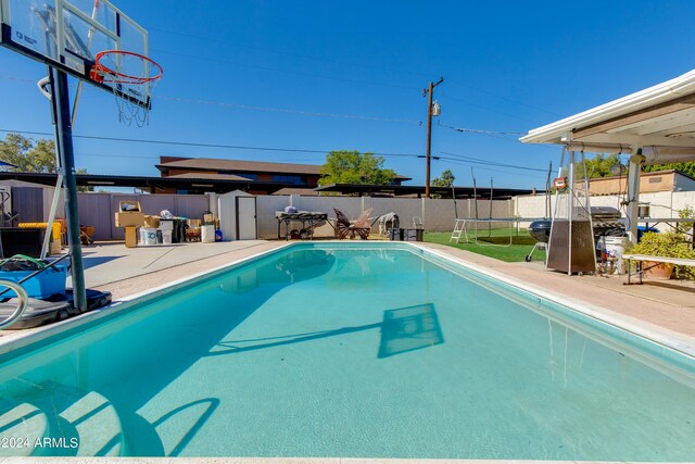 view of swimming pool with a patio area, a storage shed, and a trampoline