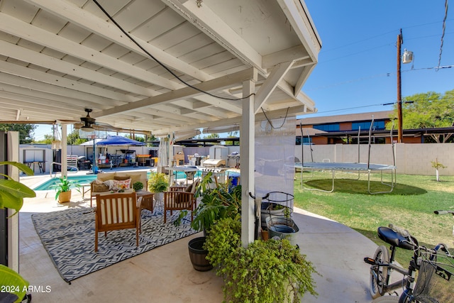 view of patio featuring a trampoline, a fenced in pool, and ceiling fan