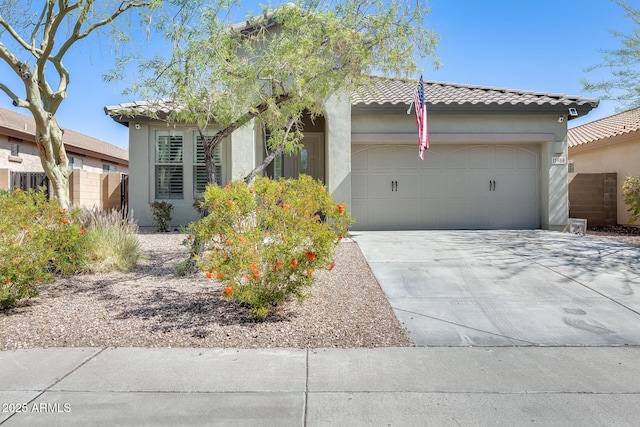 view of front facade featuring an attached garage, a tile roof, fence, concrete driveway, and stucco siding