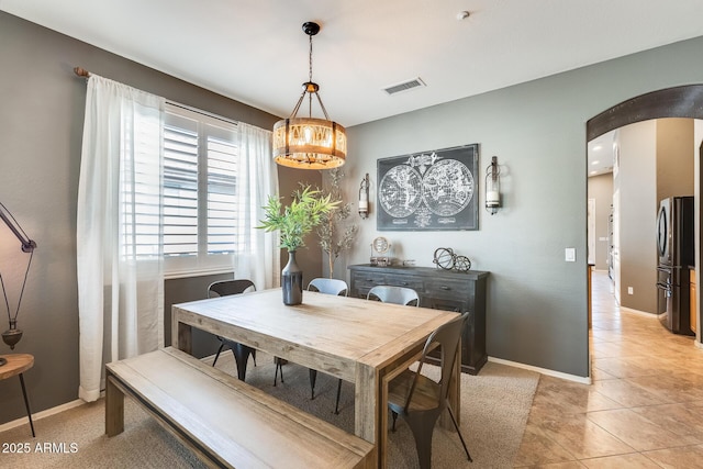 dining area with baseboards, an inviting chandelier, light tile patterned floors, visible vents, and arched walkways