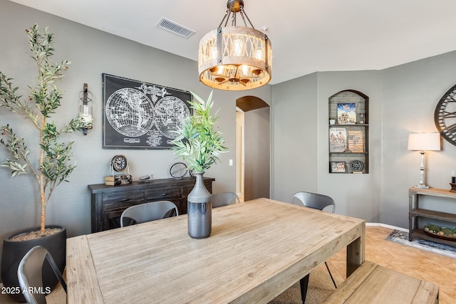 dining room featuring visible vents, baseboards, arched walkways, and tile patterned flooring