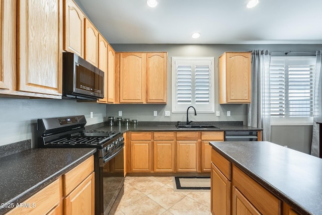 kitchen with light brown cabinets, a sink, black gas range, and dark countertops