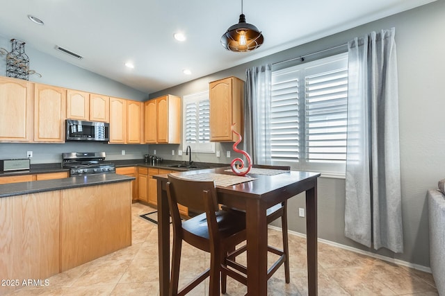 kitchen with dark countertops, visible vents, stainless steel appliances, a sink, and light brown cabinetry