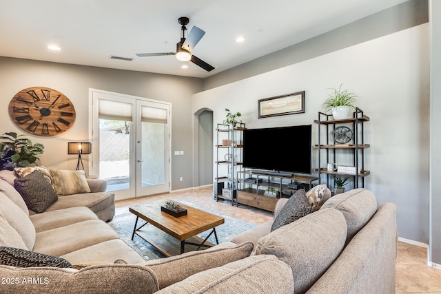 living room with visible vents, baseboards, arched walkways, a ceiling fan, and french doors