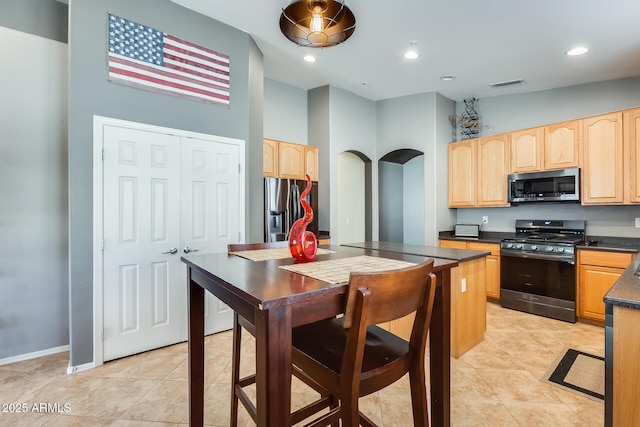 kitchen with light brown cabinets, light tile patterned floors, dark countertops, visible vents, and stainless steel appliances