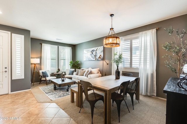 dining area with a chandelier, light tile patterned floors, and baseboards