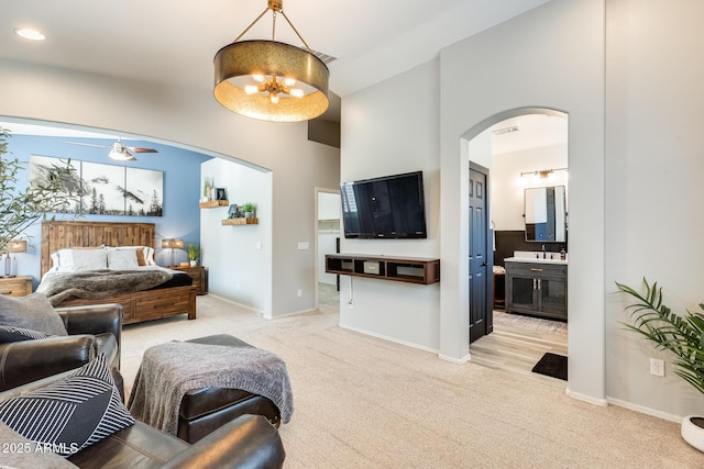 living area with visible vents, baseboards, arched walkways, ceiling fan with notable chandelier, and light carpet