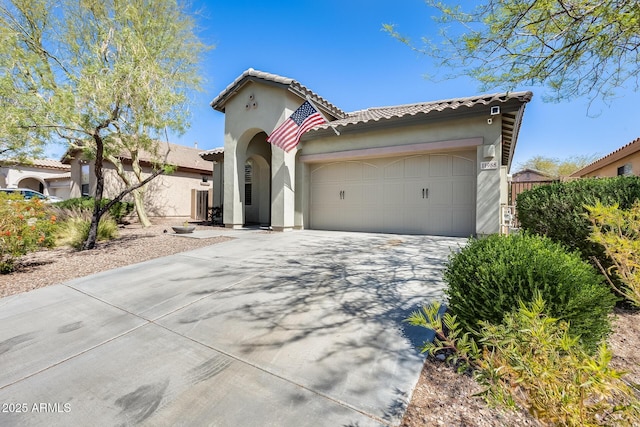 mediterranean / spanish house with concrete driveway, a tile roof, an attached garage, and stucco siding