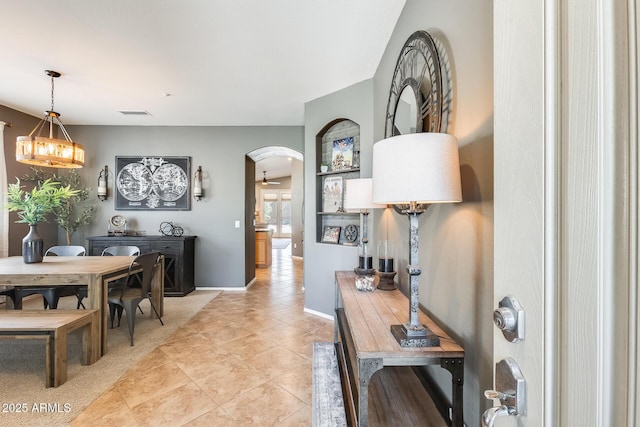 dining space featuring an inviting chandelier, baseboards, arched walkways, and light tile patterned flooring