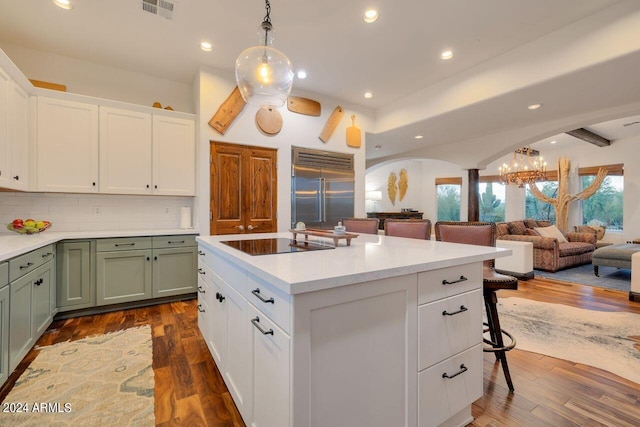 kitchen with dark wood-type flooring, green cabinetry, built in fridge, and black electric stovetop