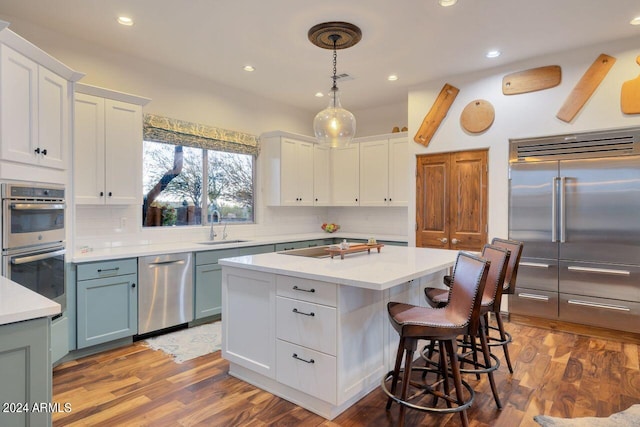 kitchen with tasteful backsplash, dark hardwood / wood-style flooring, hanging light fixtures, white cabinets, and appliances with stainless steel finishes